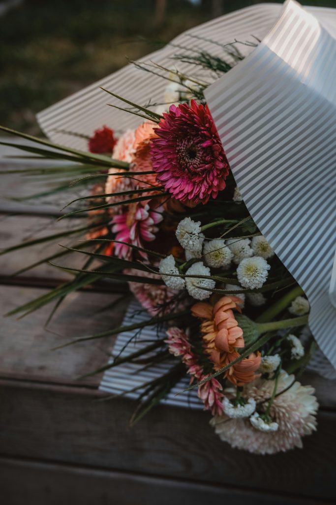 pexels-photo-26558157-26558157 Bouquet of Flowers Wrapped in Paper on a Wooden Bench